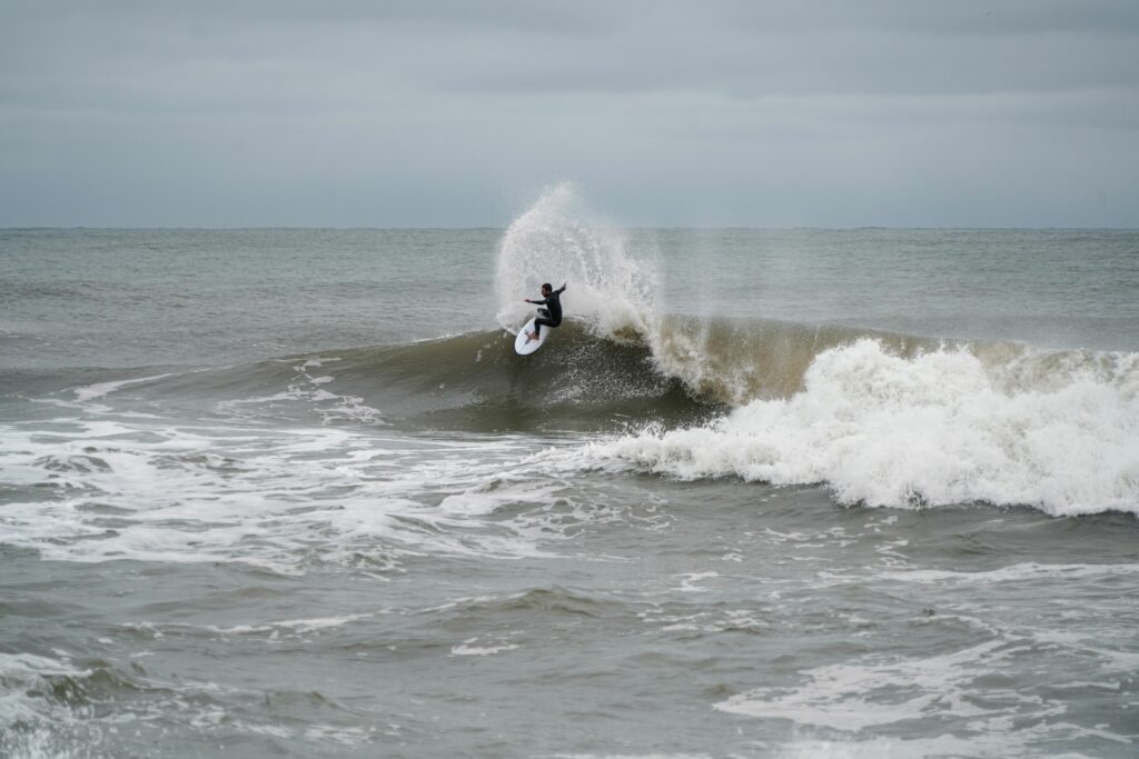 Mikey C gouging the lip while wearing his Feral Wetsuit.